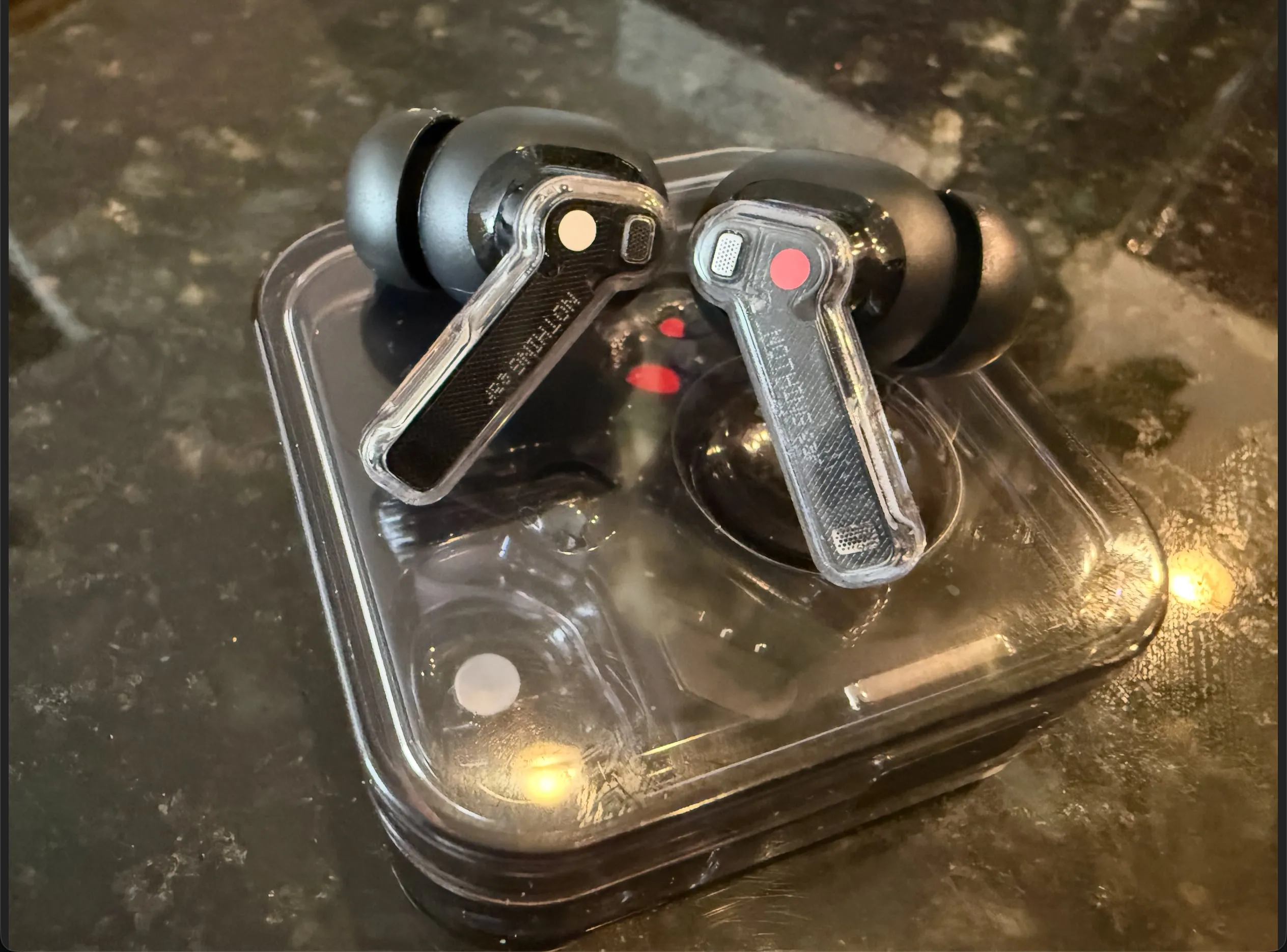 Both Nothing Ear (2024) buds with their large stock tips, resting on the closed transparent case.